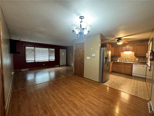 4322 Everett Ave, Kansas City, KS 66102 - unfurnished living room with light wood finished floors, a chandelier, a textured ceiling, ceiling fan, and a sink