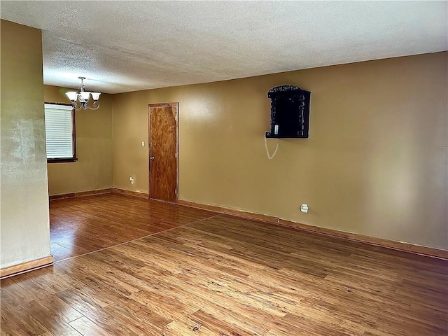 4322 Everett Ave, Kansas City, KS 66102 - spare room featuring a chandelier, wood finished floors, a textured ceiling, and baseboards