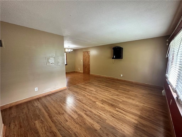 4322 Everett Ave, Kansas City, KS 66102 - empty room featuring wood finished floors, a chandelier, a textured ceiling, and baseboards