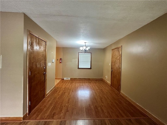 4322 Everett Ave, Kansas City, KS 66102 - empty room with a chandelier, wood finished floors, baseboards, and a textured ceiling