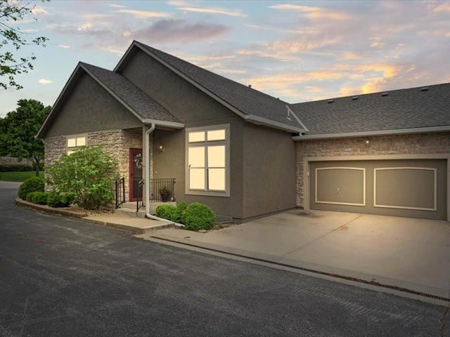 11179 S Summit St, Olathe, KS 66062 - view of front of house with roof with shingles, a garage, concrete driveway, stone siding, and stucco siding