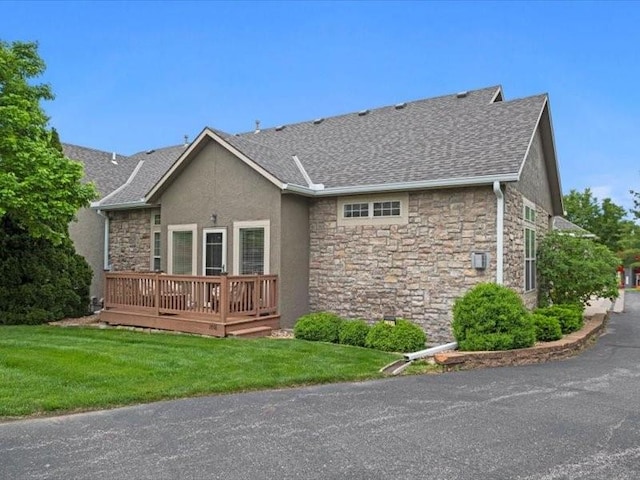 11179 S Summit St, Olathe, KS 66062 - rear view of house featuring a lawn, roof with shingles, a wooden deck, and stone siding