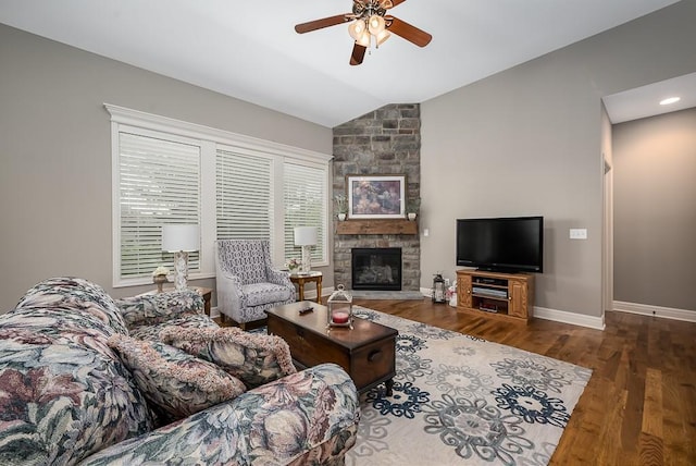 living area featuring a stone fireplace, a ceiling fan, baseboards, wood finished floors, and lofted ceiling