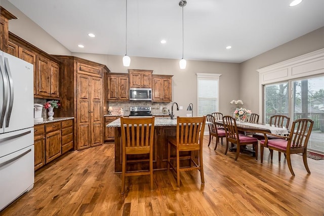 kitchen featuring backsplash, appliances with stainless steel finishes, wood finished floors, and a healthy amount of sunlight