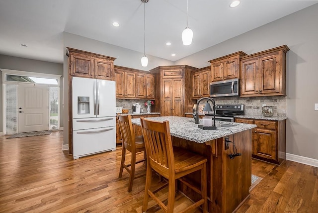 kitchen with light stone countertops, stainless steel appliances, baseboards, tasteful backsplash, and dark wood-style floors