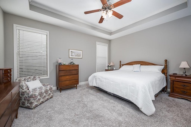 carpeted bedroom with baseboards, ornamental molding, a ceiling fan, and a tray ceiling
