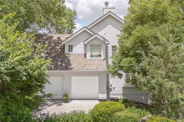 26266 W 110th Ter, Olathe, KS 66061 - view of front of house featuring concrete driveway, a chimney, an attached garage, and a shingled roof