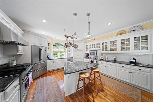 26266 W 110th Ter, Olathe, KS 66061 - kitchen with appliances with stainless steel finishes, a breakfast bar area, white cabinetry, a kitchen island, and glass insert cabinets