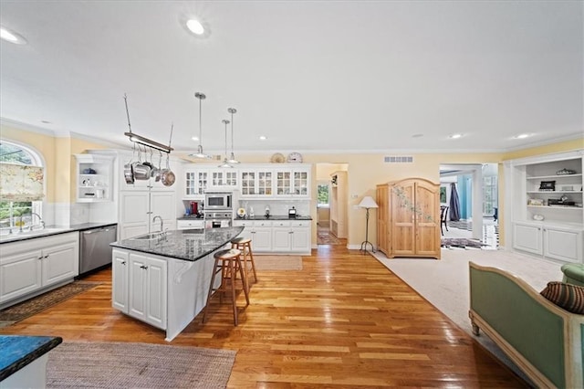 26266 W 110th Ter, Olathe, KS 66061 - kitchen with appliances with stainless steel finishes, ornamental molding, a breakfast bar, white cabinetry, and glass insert cabinets