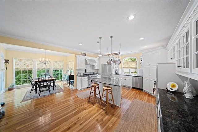 26266 W 110th Ter, Olathe, KS 66061 - kitchen with stainless steel appliances, a chandelier, ventilation hood, ornamental molding, and white cabinets
