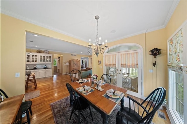 26266 W 110th Ter, Olathe, KS 66061 - dining space featuring french doors, ornamental molding, light wood finished floors, a chandelier, and healthy amount of natural light