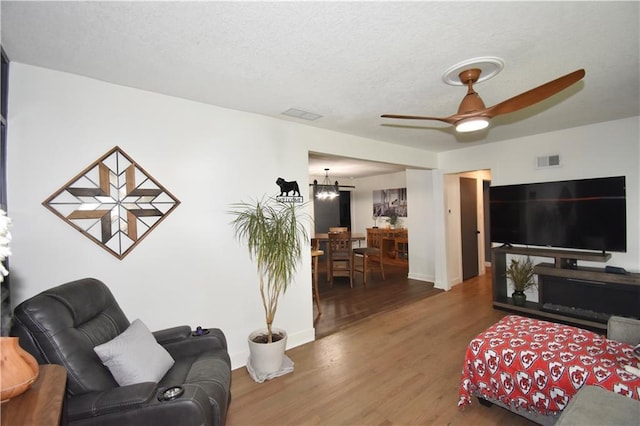 5233 N Garfield Ave, Kansas City, MO 64118 - living area featuring wood finished floors, ceiling fan, baseboards, a chandelier, and a textured ceiling