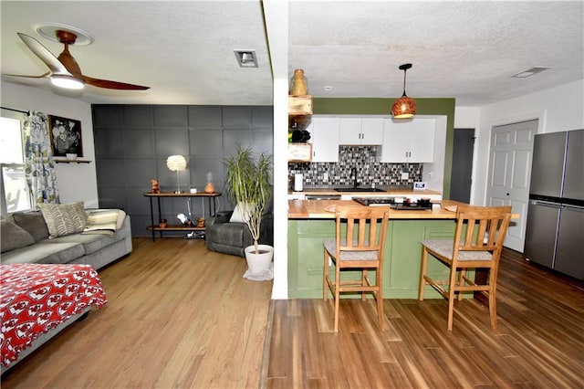 5233 N Garfield Ave, Kansas City, MO 64118 - kitchen with butcher block countertops, freestanding refrigerator, wood finished floors, a ceiling fan, and a textured ceiling