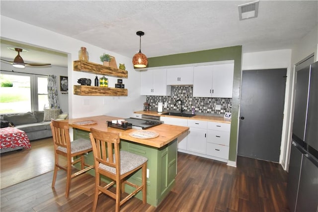 5233 N Garfield Ave, Kansas City, MO 64118 - kitchen featuring butcher block countertops, a sink, a breakfast bar, white cabinets, and freestanding refrigerator