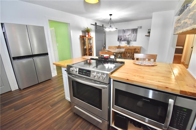 5233 N Garfield Ave, Kansas City, MO 64118 - kitchen with wooden counters, stainless steel appliances, a barn door, dark wood finished floors, and pendant lighting
