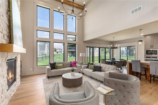 2314 SW Serena Pl, Lees Summit, MO 64082 - living area featuring a chandelier, a towering ceiling, a fireplace, and light wood finished floors