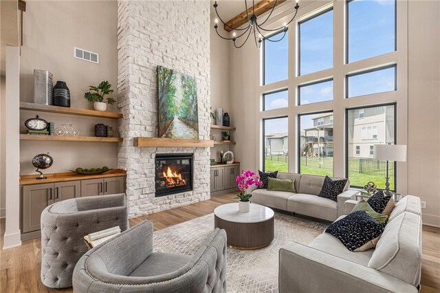 2314 SW Serena Pl, Lees Summit, MO 64082 - living room with light wood-style flooring, a towering ceiling, a fireplace, and a chandelier