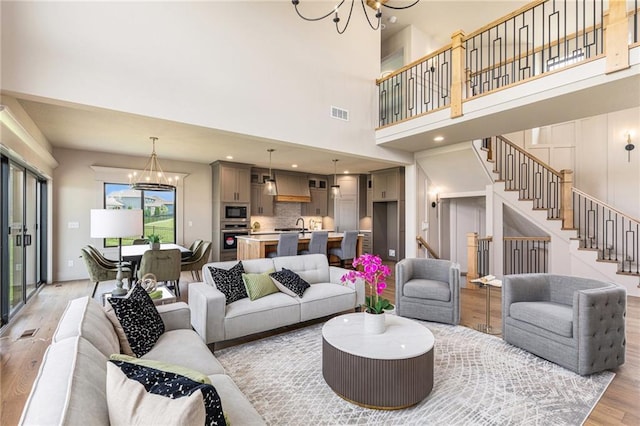 2314 SW Serena Pl, Lees Summit, MO 64082 - living area featuring a chandelier, light wood-style flooring, stairway, and a high ceiling