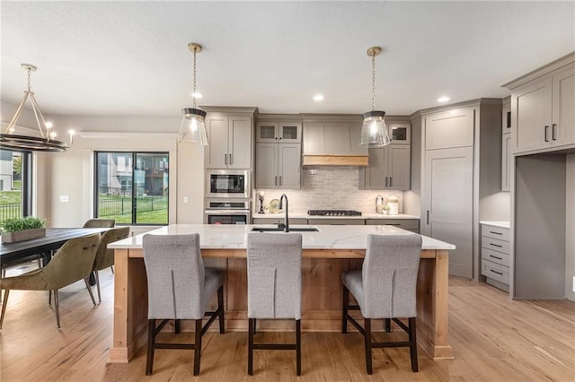 2314 SW Serena Pl, Lees Summit, MO 64082 - kitchen with gray cabinetry, appliances with stainless steel finishes, premium range hood, light wood-style flooring, and recessed lighting