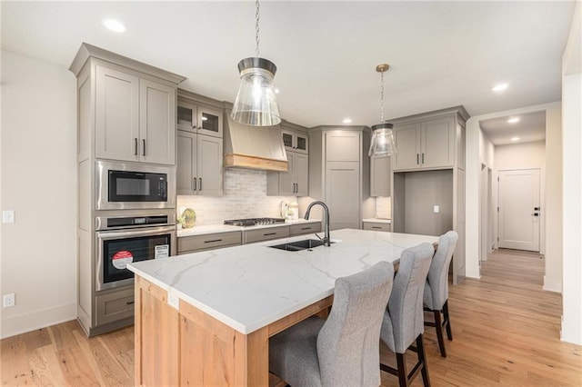 2314 SW Serena Pl, Lees Summit, MO 64082 - kitchen featuring appliances with stainless steel finishes, gray cabinets, light wood-style flooring, tasteful backsplash, and light stone countertops