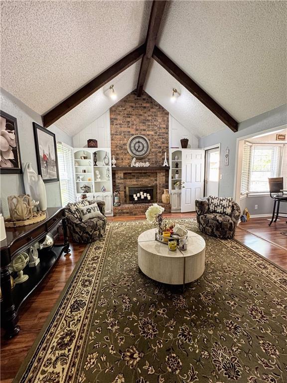 4024 NE 59th Ter, Gladstone, MO 64119 - living area with a textured ceiling, lofted ceiling with beams, wood finished floors, and a fireplace