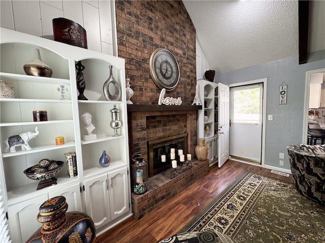 4024 NE 59th Ter, Gladstone, MO 64119 - living area featuring a brick fireplace, a textured ceiling, dark wood-style flooring, and vaulted ceiling