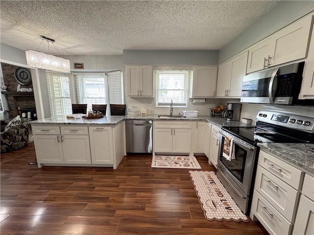 4024 NE 59th Ter, Gladstone, MO 64119 - kitchen with a textured ceiling, a sink, a peninsula, dark wood-style floors, and stainless steel appliances
