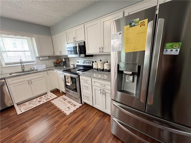 4024 NE 59th Ter, Gladstone, MO 64119 - kitchen with a textured ceiling, appliances with stainless steel finishes, dark wood finished floors, a sink, and white cabinetry