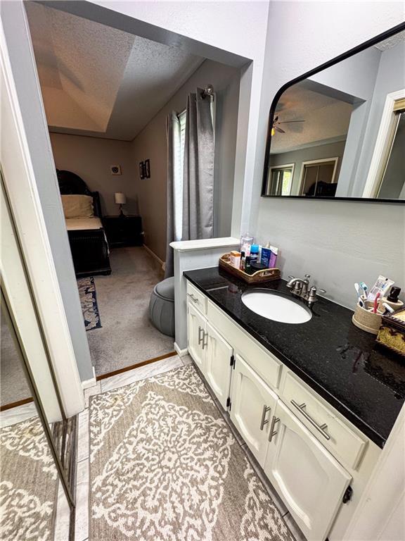 4024 NE 59th Ter, Gladstone, MO 64119 - bathroom featuring vanity, connected bathroom, a textured ceiling, and ceiling fan