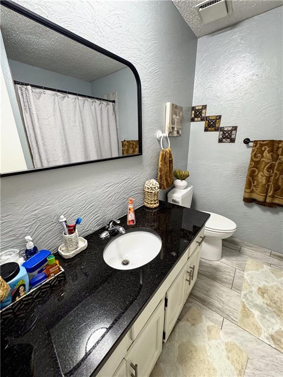4024 NE 59th Ter, Gladstone, MO 64119 - full bath with vanity, toilet, a textured ceiling, and visible vents