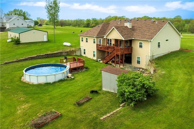 rear view of house featuring a lawn, a deck, an outdoor pool, stairway, and an outdoor structure