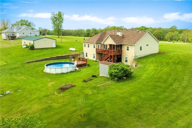 back of property featuring an outdoor pool, a wooden deck, a yard, and stairway