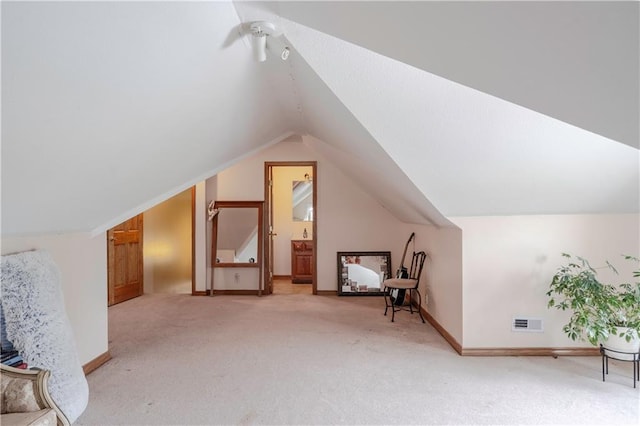 additional living space with light carpet, a ceiling fan, baseboards, vaulted ceiling, and visible vents