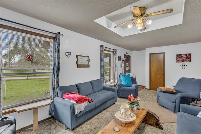 living area featuring baseboards, carpet, a ceiling fan, and a textured ceiling