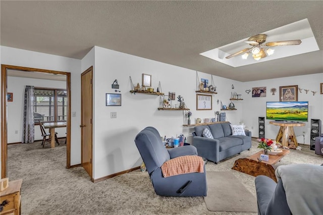 carpeted living area with baseboards, a ceiling fan, a textured ceiling, and a skylight