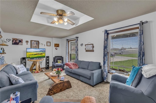 living room with plenty of natural light, carpet, ceiling fan, and a tray ceiling