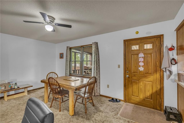 dining area featuring baseboards, a ceiling fan, a textured ceiling, and light carpet