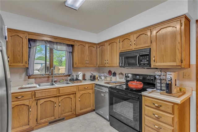 kitchen with a sink, light countertops, black appliances, and visible vents
