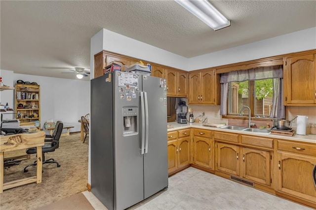kitchen featuring a sink, stainless steel fridge with ice dispenser, light countertops, a ceiling fan, and visible vents