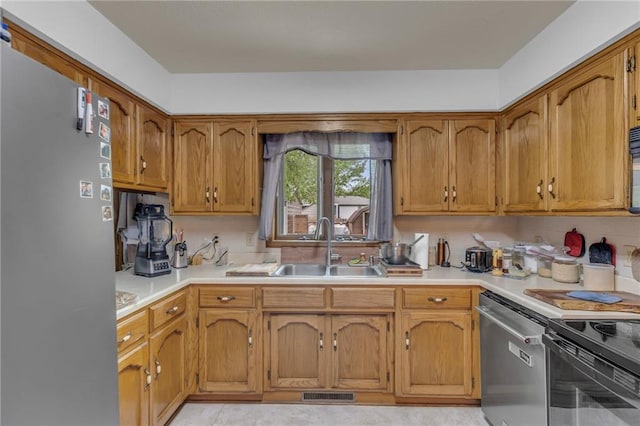 kitchen with light countertops, appliances with stainless steel finishes, a sink, and visible vents