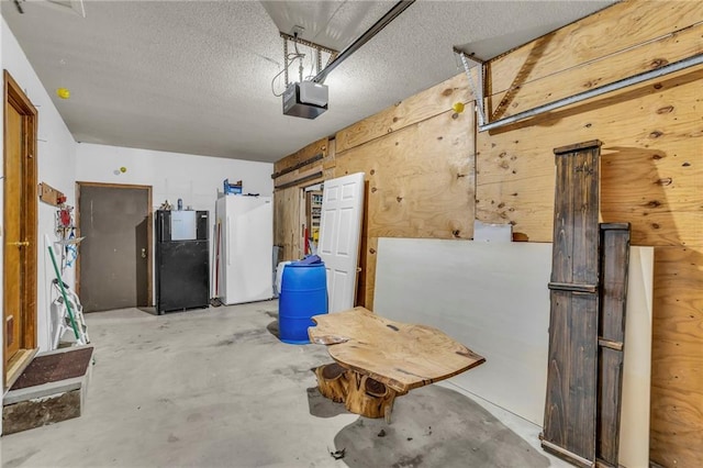 garage featuring wooden walls, a garage door opener, and freestanding refrigerator
