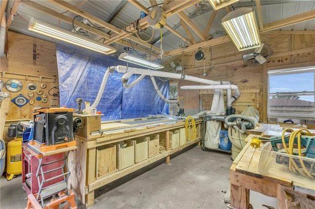 misc room with wood walls, concrete floors, and lofted ceiling
