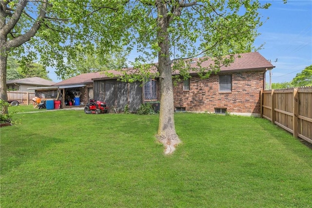 rear view of property featuring a lawn, brick siding, a fenced backyard, and roof with shingles