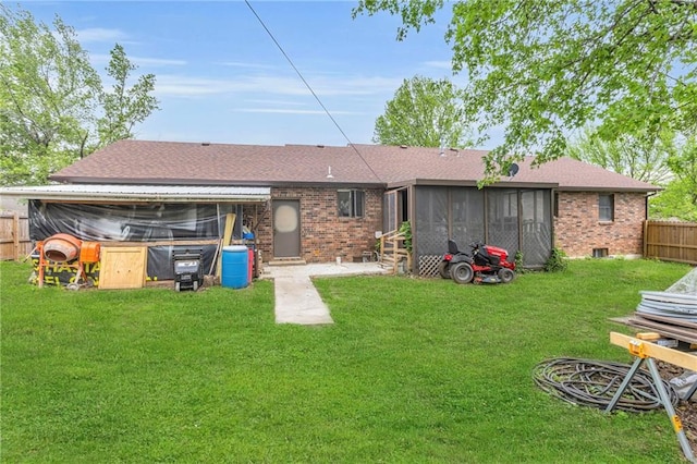 back of house featuring a yard, brick siding, a fenced backyard, and a sunroom