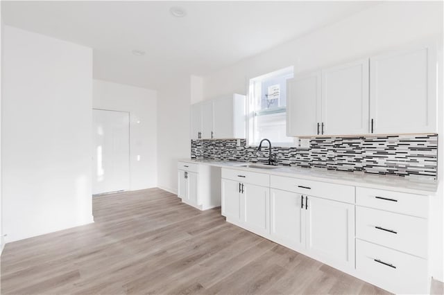 kitchen featuring a sink, light countertops, decorative backsplash, white cabinetry, and light wood-style floors