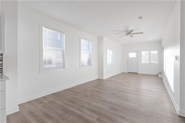 unfurnished living room featuring light wood finished floors, ceiling fan, and baseboards