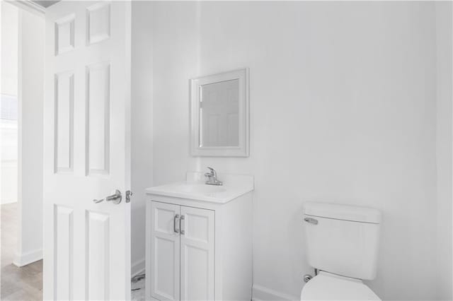 bathroom with toilet, vanity, baseboards, and wood finished floors