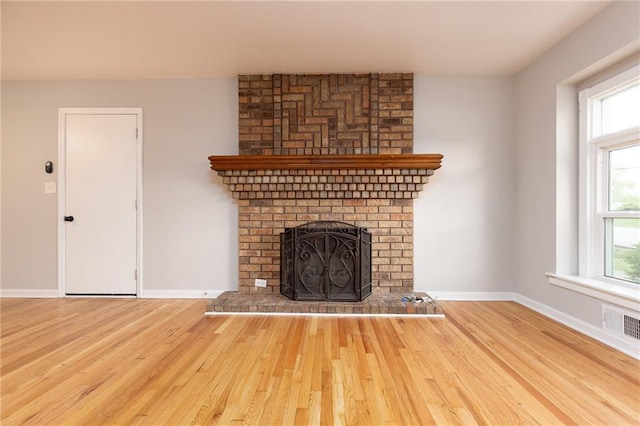 unfurnished living room featuring baseboards, wood finished floors, visible vents, and a fireplace