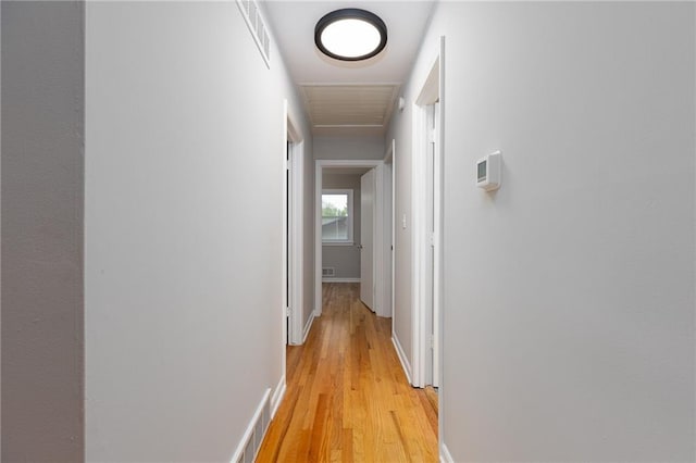 corridor with baseboards, visible vents, and light wood-style floors