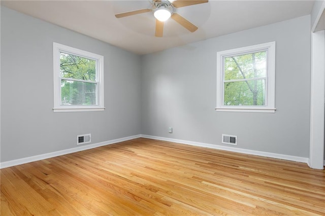 unfurnished room featuring visible vents, light wood-style floors, and plenty of natural light